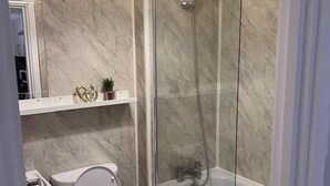 A modern bathroom with a toilet, a glass-enclosed shower, and a bathtub.