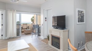 Een moderne woonkamer met een flatscreen televisie, een open haard en een balkon met tuinmeubilair.