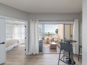 Een hotelkamer met een bed, een balkon met tafel en stoelen, en uitzicht op het strand.