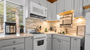 Une cuisine moderne avec des meubles blancs, une cuisinière encastrée et un four à micro-ondes.