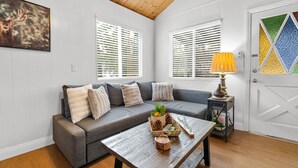 Un salon avec un canapé gris, une table basse en bois et une porte ornée de panneaux de verre colorés.