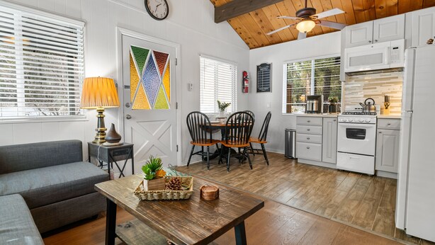 Une cuisine moderne avec des meubles blancs, un plafond en bois et un coin repas comprenant une table et des chaises.