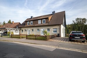 A residential house with a tiled roof, a front porch, and a parked car.