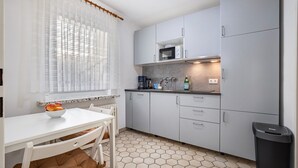 A compact kitchen with white cabinets, a microwave, a sink, and a trash bin. - Apartment "Große" with Mountain View, Terrace & Wi-Fi (Osterode am Harz)