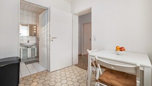 A room with a white table, a white chair, a brown cushion, a white sink, and a mirror with lights. - Apartment "Große" with Mountain View, Terrace & Wi-Fi (Osterode am Harz)