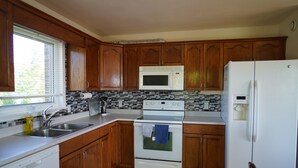 A kitchen with wooden cabinets, a white refrigerator, a microwave, an oven, and a dishwasher. - Great Location - North Rustico Ocean View (North Rustico)