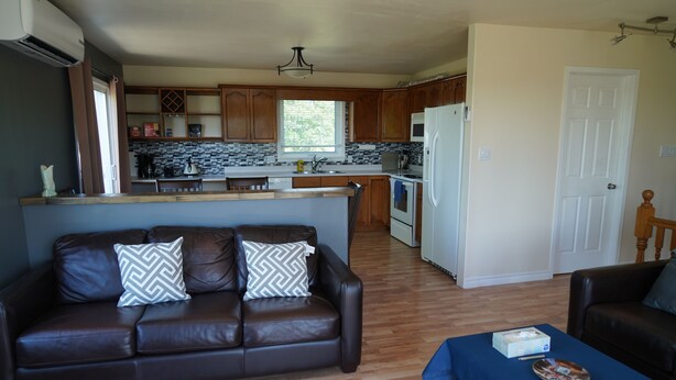 A modern kitchen with wooden cabinets, a central island, and a microwave. - Great Location - North Rustico Ocean View (North Rustico)