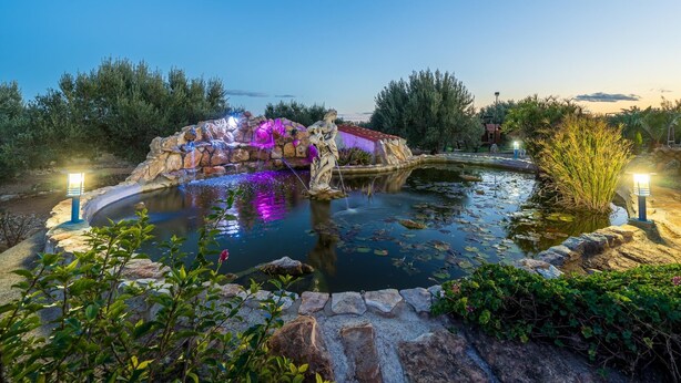 Un jardín tranquilo al aire libre con un estanque, un puente de piedra y una estatua.