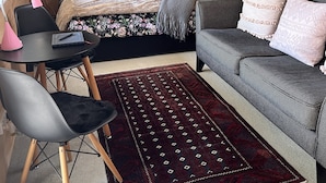 A cozy room with a bed, a sofa, a desk, and a chair. There is a window, a hanging light, and a wall-mounted rack. - Kākā Ridge Retreat Bush Hideaway (Tawharanui Peninsula)