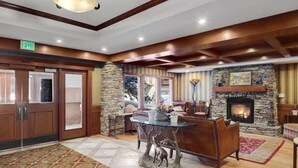 A lobby with a stone fireplace, a dining area with a glass table, and a reception desk.