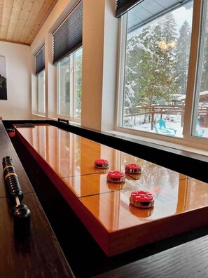 A wooden bar with a polished surface and red buttons, large windows with a view of snow-covered trees.