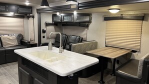 A compact RV kitchen with a sink, a dining area, and a seating space. - The Little Sweet Home (Spring Hill)