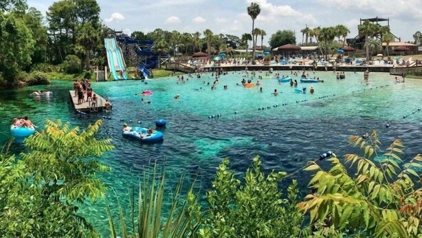 A water park with clear blue water, inflatable rafts, and a large slide. - The Little Sweet Home (Spring Hill)