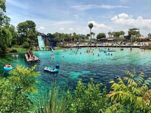 Ein Wasserpark mit klarem, blauem Wasser, aufblasbaren Ringen und einer großen Rutsche.