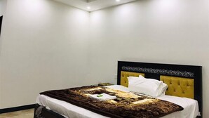 Een slaapkamer met een bed, een plafondventilator, inbouwspots en een effen muur.