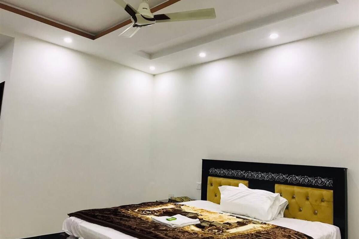 Ein Schlafzimmer mit einem Bett, Deckenventilator, Einbauleuchten und einer schlichten Wand.