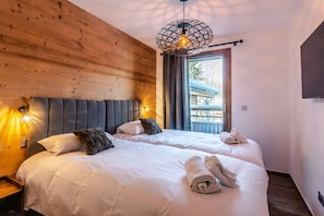 A double room with two beds, a wooden wall, a modern pendant light, and a view of the outside. - Best location in Morzine, direct access to Avoriaz (MORZINE)