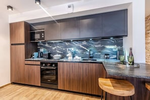 A modern kitchen with dark wood cabinets, a black countertop, and a marble backsplash. - Best location in Morzine, direct access to Avoriaz (MORZINE)