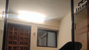 Um quarto com porta de madeira, janela, cadeira e mesa.