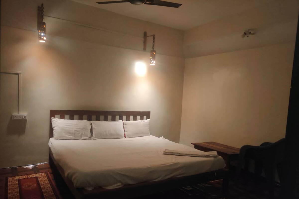 Quarto com cama, ventilador de teto e duas luzes fixadas na parede.