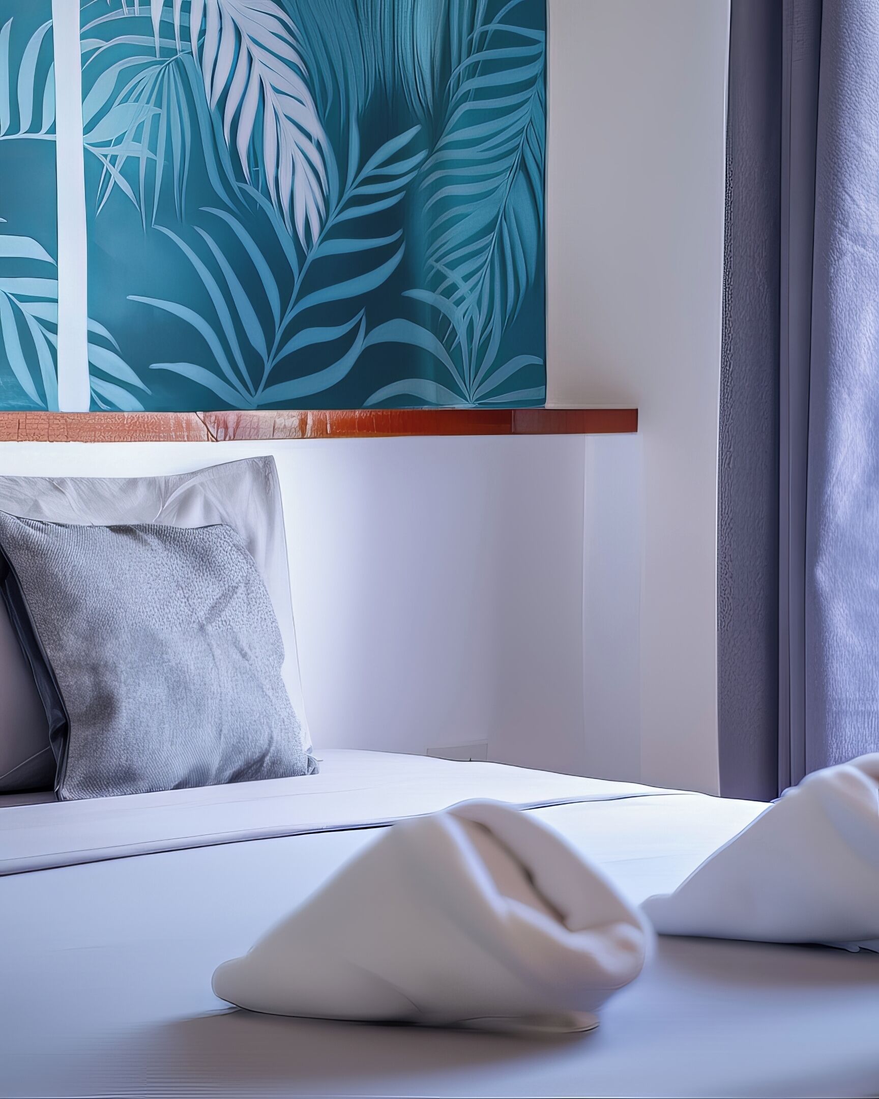A neatly made bed with white linens, a grey pillow, and a teal leaf-patterned wall hanging above it.