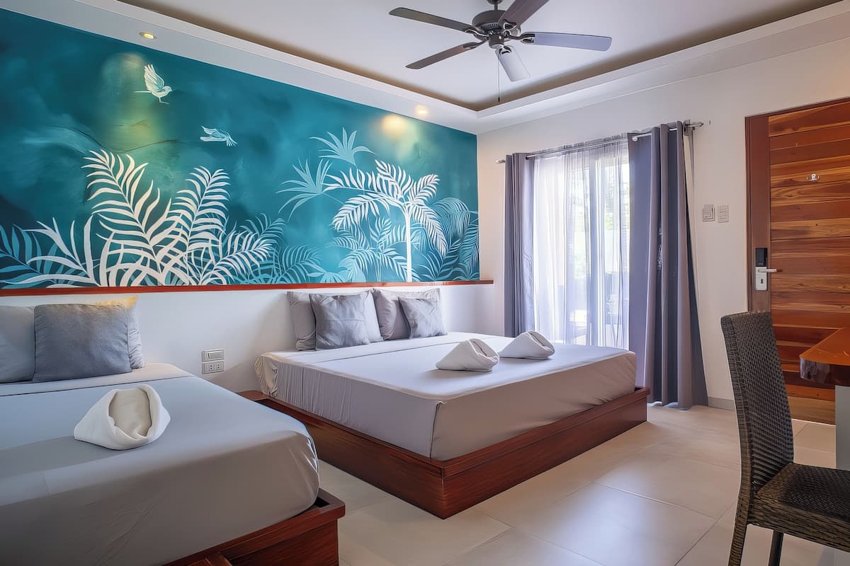 A modern hotel room with a large tropical mural, a ceiling fan, and a view of the outdoors through a window.