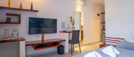 A modern hotel room with a large bed, a TV, a desk, and a mirror.