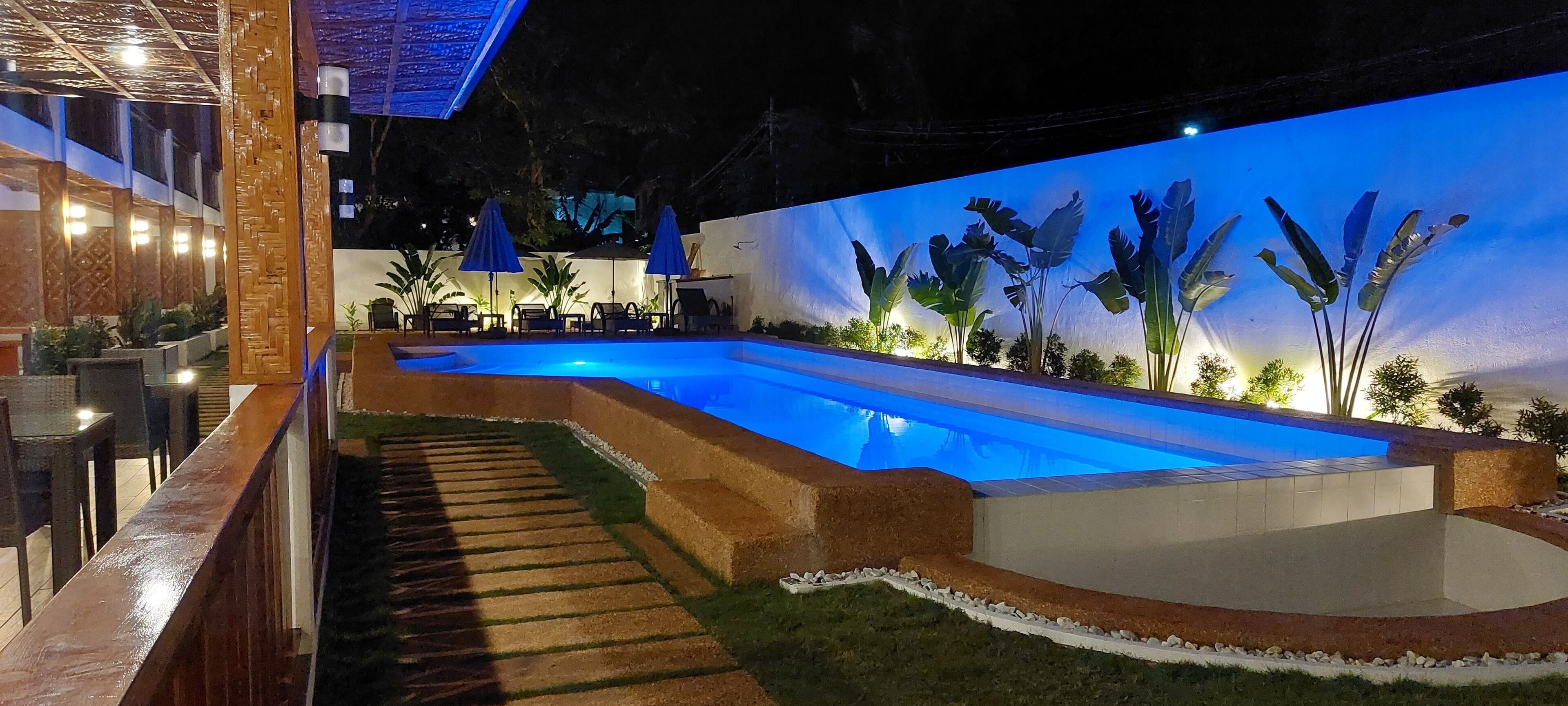 An outdoor swimming pool area with a decorative wall, lounge chairs, and a wooden deck.