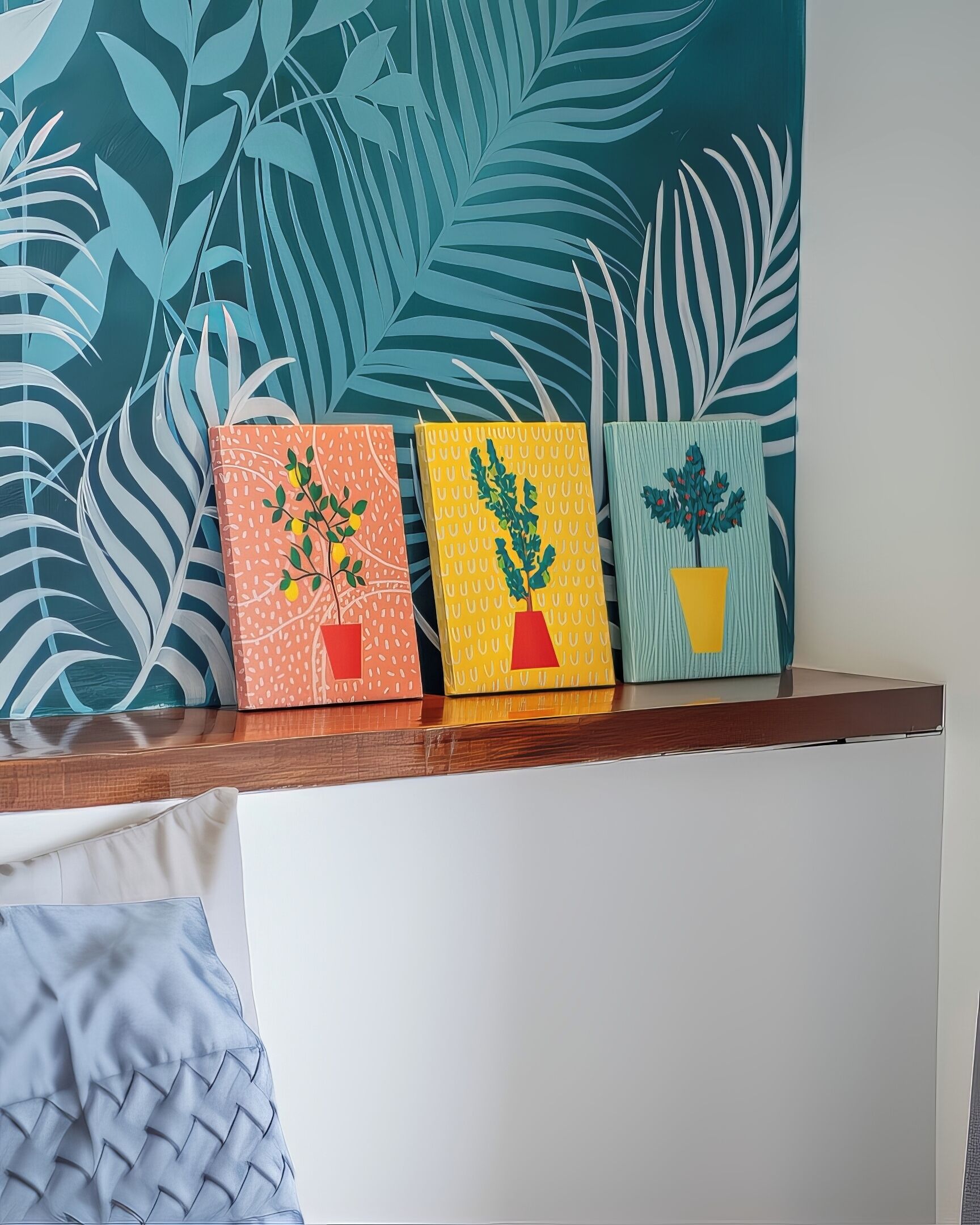 Three potted plants on a wooden shelf against a wall with a leaf pattern.