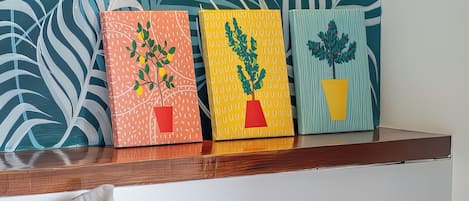 Drie potplanten op een houten plank voor een muur met een bladmotief.