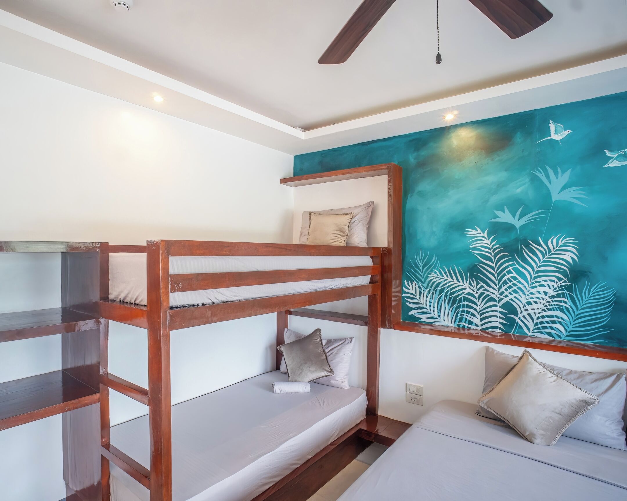 A bunk bed room with a mural of birds and foliage on the wall.