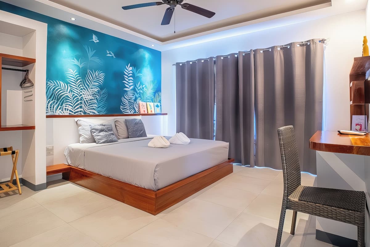 A modern bedroom with a bed, a ceiling fan, a large wall mural, and a window with curtains.