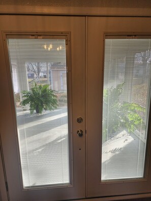 Una puerta con dos ventanas, cada una con persianas horizontales, y una cerradura en el centro.