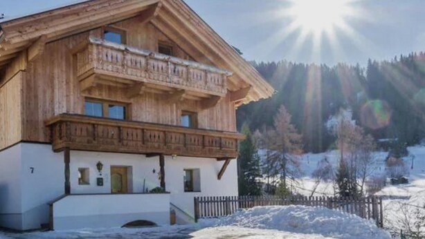 A wooden chalet with a balcony, a white facade, and a snowy landscape in the background. - Spacious apartment near the ski lift (Fendels)