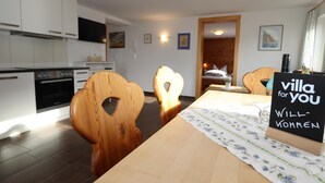 A modern kitchen with white cabinets and a built-in oven. There is a dining table with a floral tablecloth and a sign that reads "villa for you Willkommen". - Spacious apartment near the ski lift (Fendels)