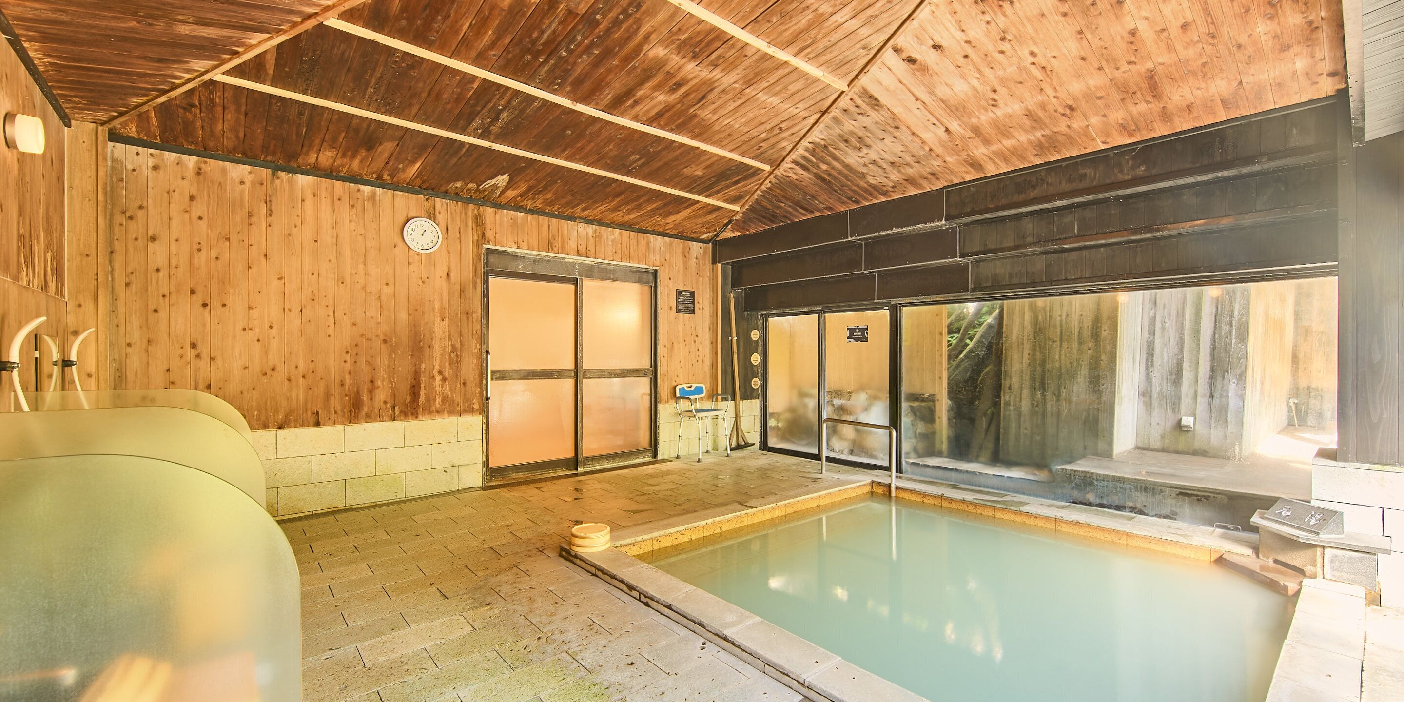 A wooden interior with a pool, a sauna, and a massage chair.