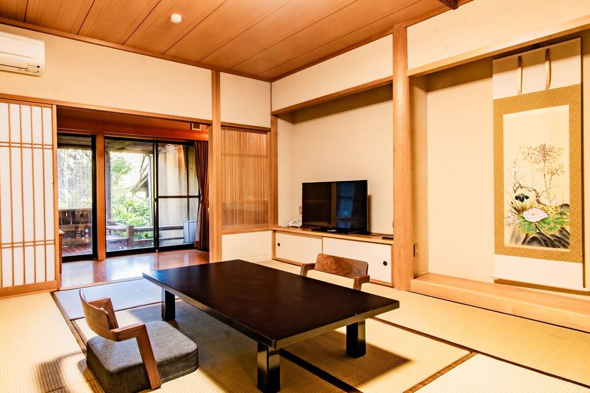 Une pièce de style japonais traditionnel, avec un sol recouvert de tatamis, une table basse et un téléviseur.