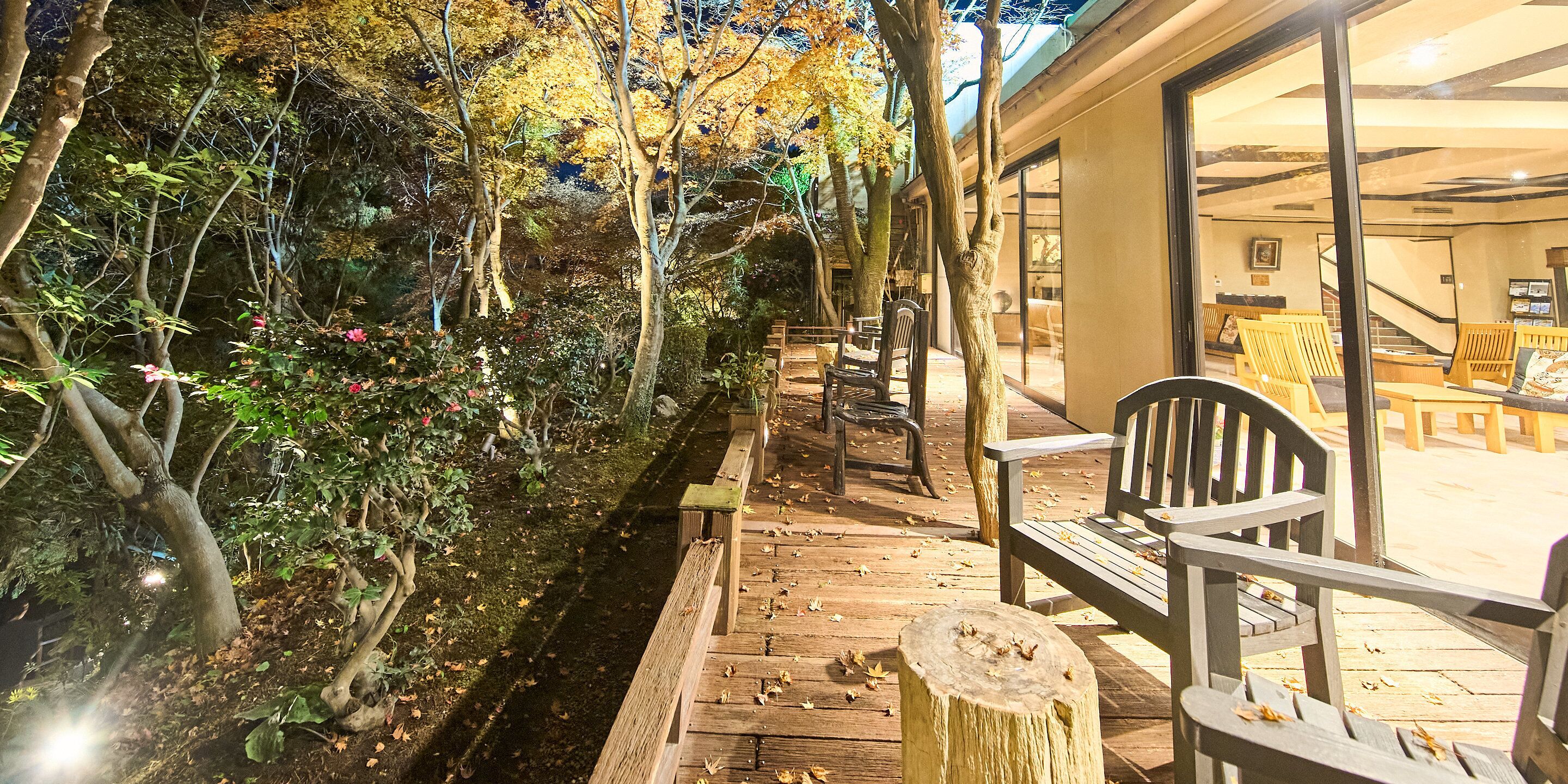 Eine Holzterrasse mit Bänken, einem Steinsockel und einem von Bäumen und Vegetation gesäumten Pfad.