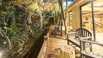 Eine Holzterrasse mit Bänken, einem Steinsockel und einem von Bäumen und Vegetation gesäumten Pfad.