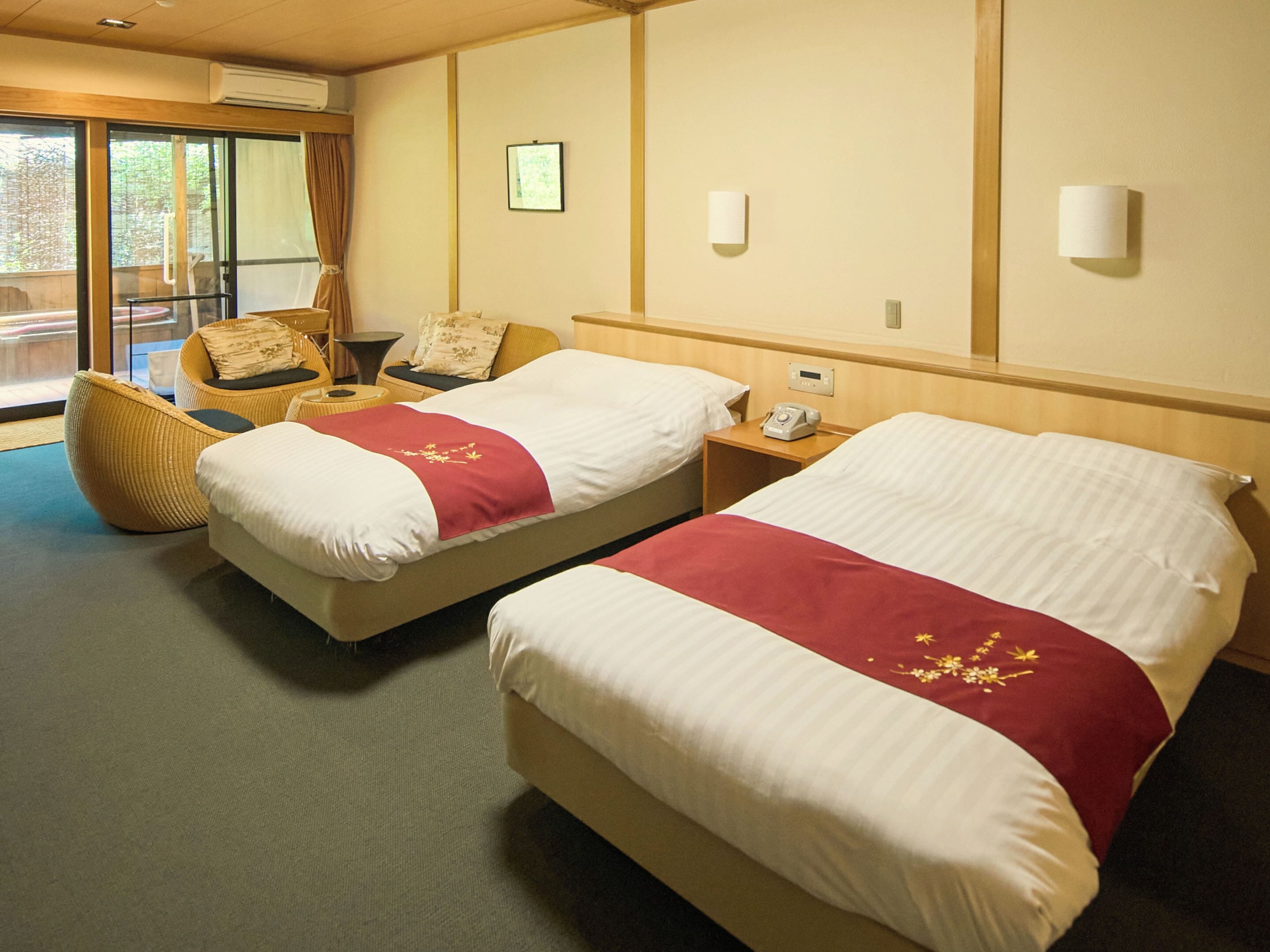 A hotel room with two beds, a chair, a nightstand, and a window with curtains.
