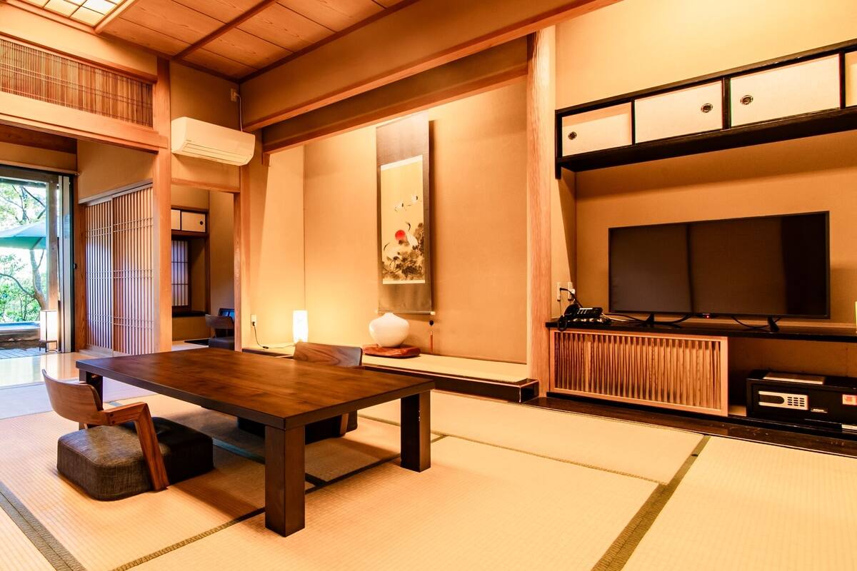 Une pièce de style japonais traditionnel, avec un sol recouvert de tatamis, une table basse et un téléviseur.