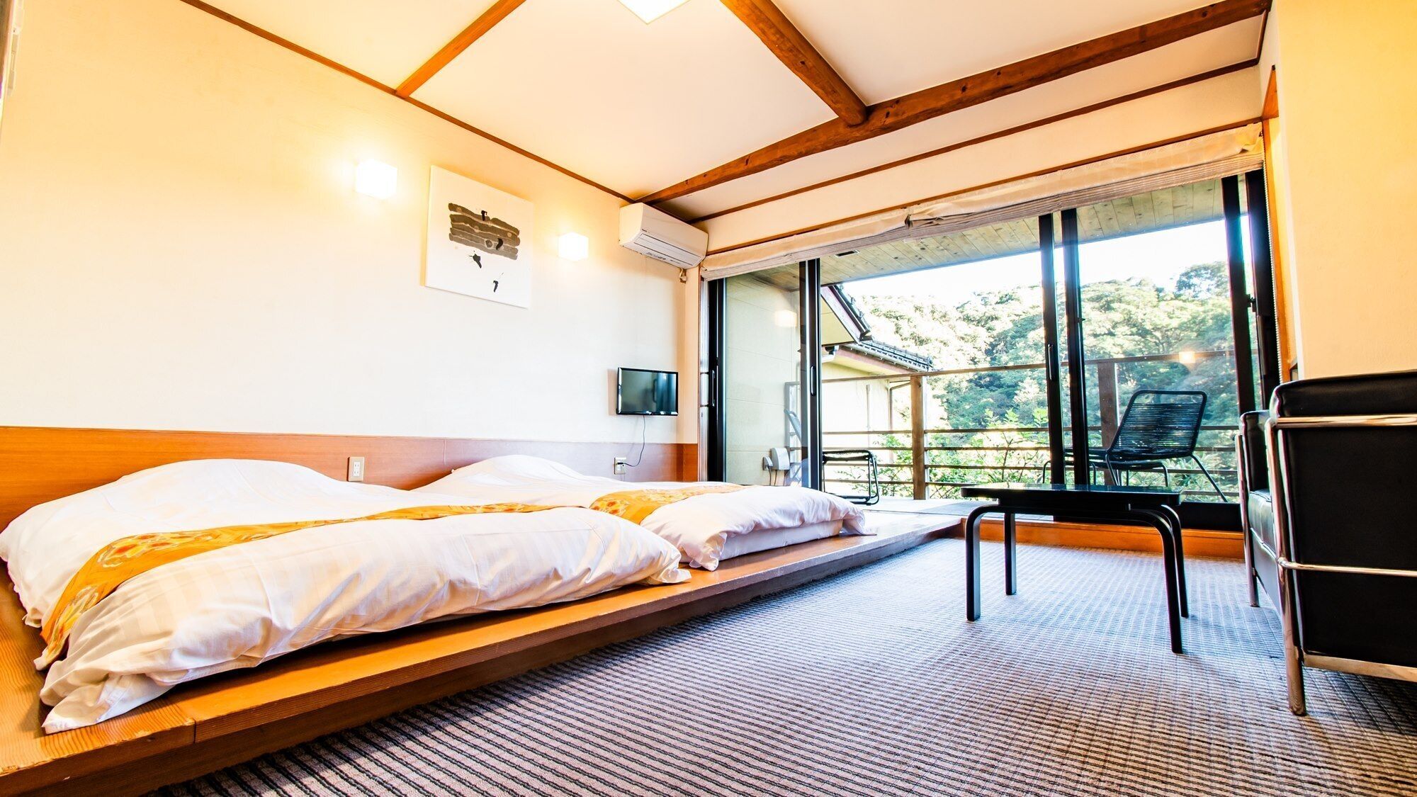 A bedroom with two beds, a TV, and a balcony with a chair.