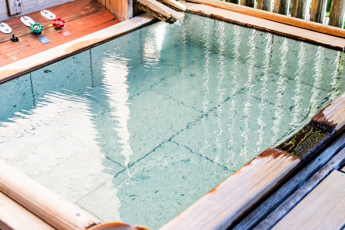 Una terraza de madera con una piscina pequeña, rodeada de barandillas de madera.