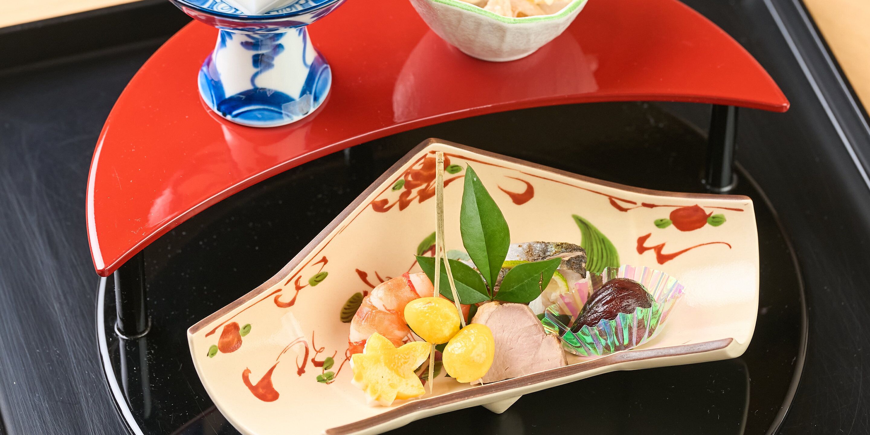 A traditional Japanese meal served on a black tray with a red cover.