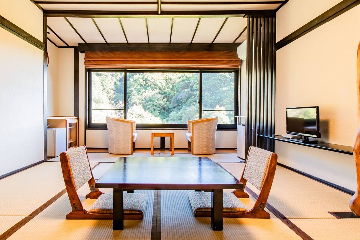 Une pièce de style japonais traditionnel, avec un sol recouvert de tatamis, une table basse et deux tatamis servant de coussins.