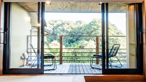 Una habitación con puerta corrediza de vidrio que da a una terraza exterior con dos sillas y una mesa.