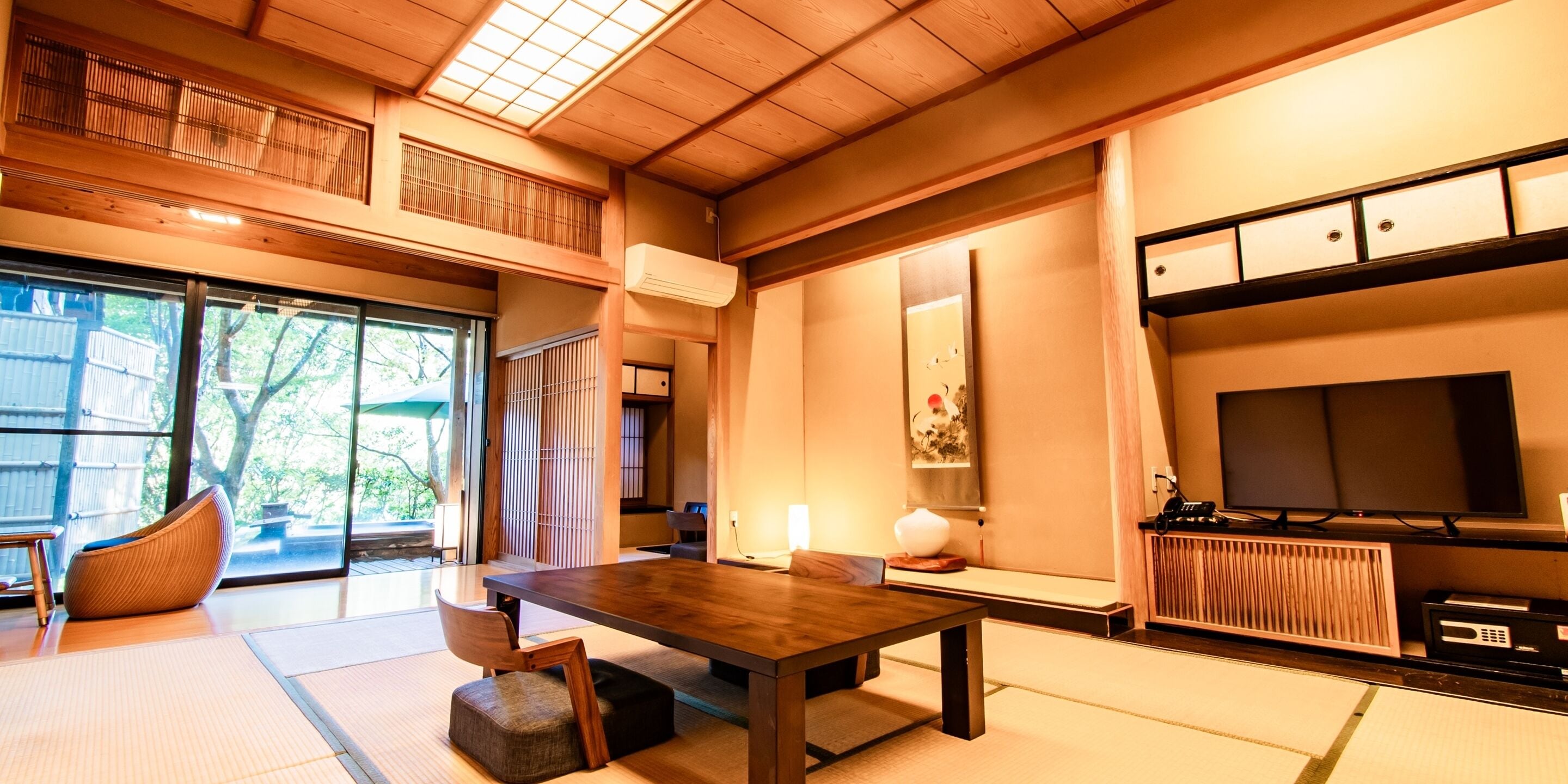 A traditional Japanese-style room with tatami flooring, a low wooden table, and a television.