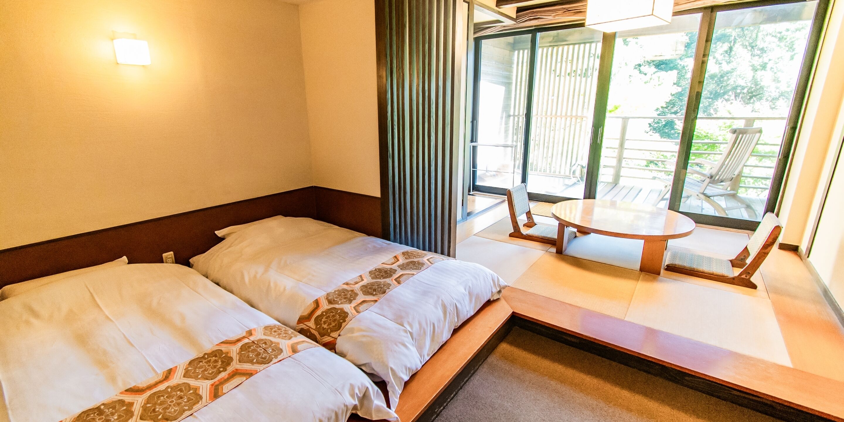 Habitación de hotel con dos camas, una mesita y vistas al exterior.