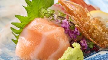 A dish with sashimi, a piece of fried seafood, and a lemon wedge.