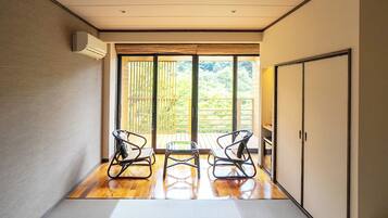 A hallway with a wooden floor, two rocking chairs, a sliding glass door leading to a balcony, and a wardrobe.